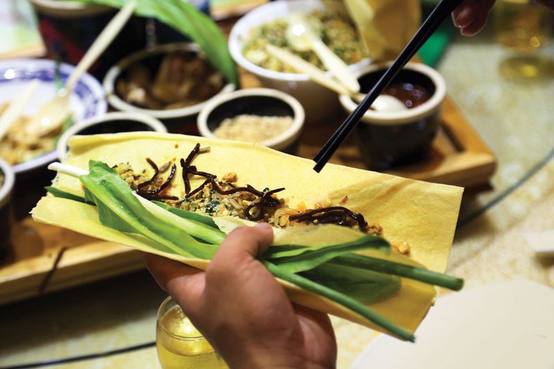 A chef wraps vegetables, pickles, and peanuts in a Shandong jianbing