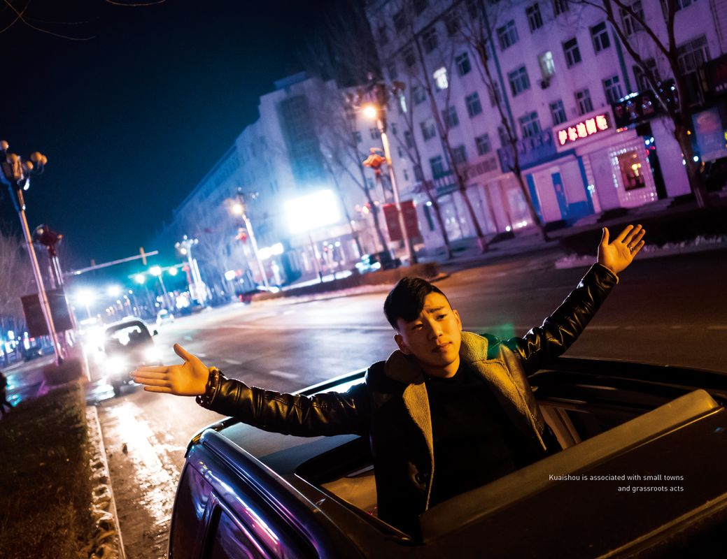 Image of a Chinese man extending out his hands while standing through the car's moonroof