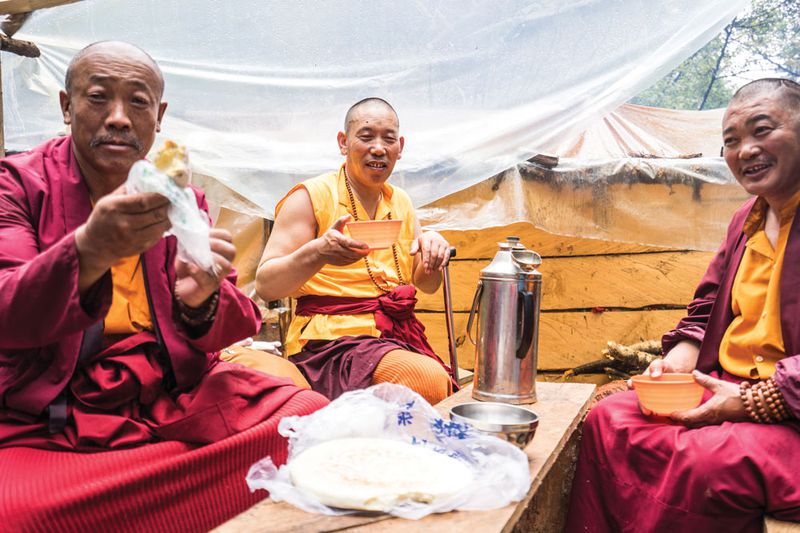 Monks making their pilgrimage from Garze county, Sichuan province, offer to share a lunch of cakes made with highland barley