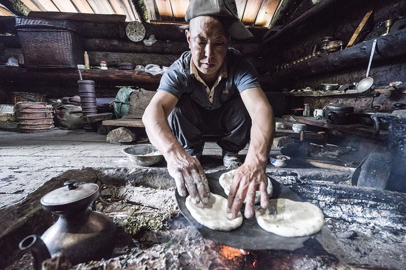 A herdsman at the camp invites visitors for a snack and yak-butter tea