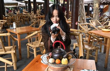 Young Chinese photographer taking photos of her tea